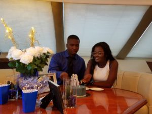 A beautiful couple cutting a cake on the yacht
