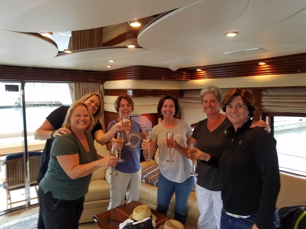 A group of women enjoying a private yacht charter and toasting with wine glasses