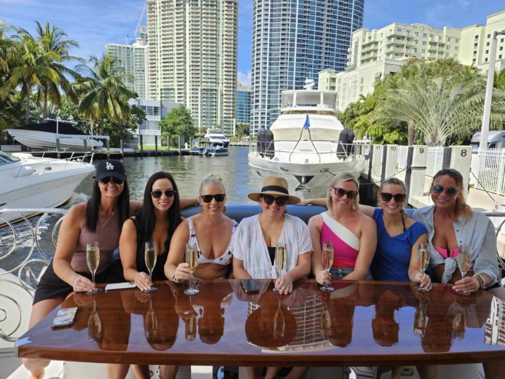 Group of women are enjoying the scenery from the aft of our luxury yacht. They celebrate with champagne and enjoy the south Florida sights along the waterways.